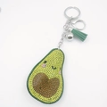 Détail d'un porte-clés avocat serti de strass avec pompon vert et fermoir mousqueton argenté - Visage Souriant Jaune