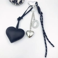 Detail of black leather heart keychain with silver diamond letter O and woven rope strap - Letter O