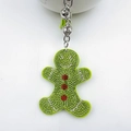 Close-up of gingerbread man keychain with light green rhinestones and silver bell - Pale Green