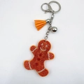 Macro detail of gingerbread man keychain with orange rhinestones and a suede tassel - Orange