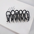 Detailed view of matte black hair claw clip with interlocking spiral teeth and metal spring - Matte Black
