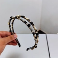 Dettaglio di un cerchietto a doppio strato con cristalli lucenti e perle sintetiche - Nero