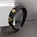Dettaglio dell'elegante cerchietto in tessuto nero plissettato con ciondoli in metallo - Nero