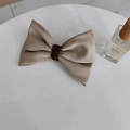 Dettaglio del fermaglio per capelli con fiocco in raso oro champagne e bottone vintage - Cachi