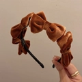 Dettaglio macro della fascia in velluto marrone con cinque fiocchi 3D e interno nero - Cuoio