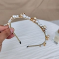 Diadema dorada elegante con perlas blancas y cristales ámbar sobre un fondo blanco puro - Champán