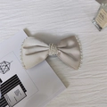 Dettaglio del fiocco in raso champagne con perle eleganti in una scena raffinata - Bianco avorio