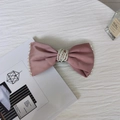 Dettaglio del fermaglio a fiocco in raso rosa cipria con bordi e centro in perline - Rosa