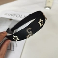 Details des schwarzen Satin-Haarreifs mit Strass-Sternen, Goldblüten und S-Buchstaben-Charms - Strass Nummer 5 Und Stern Stil