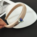 Detalle de diadema de esponja oro champán con gran cristal de corazón y placa de marca - Diadema de Mármol Beige