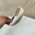 Detalle de diadema acolchada de satén champán con colgante metálico dorado grabado - Blanco Roto