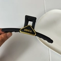 Dettaglio della pinza per capelli nera opaca con triangolo dorato e logo POWER inciso - Stile a Barra