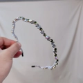 Detalle macro de cuentas de cristal artesanales y pedrería en la diadema ondulada - Gris