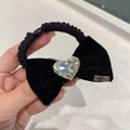 Détail d'un chouchou en velours noir avec un grand cristal de cœur et plaque métal - Cravate à cheveux