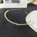 Elegante cerchietto dorato sottile con zirconi ondulati su sfondo di pelle nera - Oro