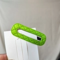 Close-up of bright green quilted PU leather oval hair clip on a display card - Green