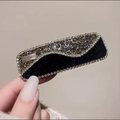 Detalle de una pinza para el cabello de terciopelo negro con pedrería y placa de metal - Estilo de Onda
