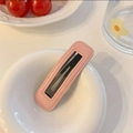 Close-up of a pink quilted faux leather BB hair clip on a white decorative plate - Pink