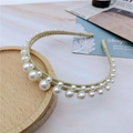 Vista detallada de una diadema de hilo dorado con perlas elegantes sobre un plato de madera - Dorado