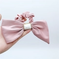 Detaillierte Makroansicht eines rosa Satin-Haargummis mit weißem Harz-Ornament-Detail - Rosa