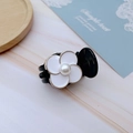 Detail of a mini camellia hair claw with white petal gold trim and a central pearl - White Clover