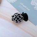 Detailed close-up of a small camellia hair claw clip with black and white resin finish - Black Rose