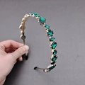 Detailed close-up of golden headband featuring multi-shaped dark green crystals - Green