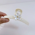 Detail of a large cream-colored hair claw clip with a white flower and golden center - Off-white