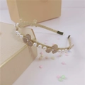 Dettaglio di cerchietto barocco con perle e quadrifogli di strass su scatola regalo - Trifoglio