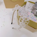 Detalle de diadema artesanal con flores de cuentas de cristal sobre caja regalo - Blanco