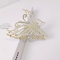 Elegante pinza de pelo de mariposa dorada con perlas sobre fondo minimalista - Estilo Perla