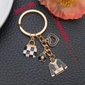 Golden keychain with black enamel heart, checkered handbag, camellia, and pearl top charms - Black Top Handbag Style / Black