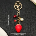 Detalle del llavero de fresa roja en resina con perla y herrajes en tono dorado - Fresa de Resina Roja Con Perla Strass
