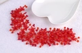 Nahaufnahme von rotem floralem Brautschmuck mit Kristallperlen und goldener Webung - Rot