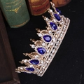 Couronne dorée vintage avec pierres bleues et strass blancs sur des livres anciens - Base Dorée Pierre Bleue