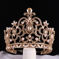 Elegante goldene Krone mit champagnerfarbenen Kristallen und rosa Perlen auf Schwarz - Champagner