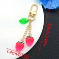 Macro detail of cute pink resin strawberry charms with green leaf and golden chain clasp - Transparent Rose Red Leaf Strawberry