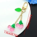 Detailed view of pink resin cherry keychain with green leaves and gold metal lobster clasp - Transparent Pink Leaf Cherry U-shaped Charm (ER1604)