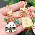 Cute panda enamel keychain featuring green bamboo charm in golden metal finish - Panda Chewing Bamboo Shoots Style (ER1126)