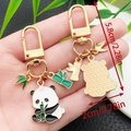 Golden panda and bamboo keychain charm with enamel finish, dimensions 5.8cm by 2cm - Panda Holding Bamboo Style (ER1134)