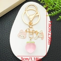 Detail of Cinnamoroll and My Melody keychain with a pink peach and golden metal charms - Pink Peach Cartoon Style (ER1615)