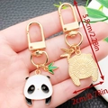 Cute panda metal keychain with green bamboo leaf charm shown in hand, golden finish - Cute Adorable Panda Style (ER1182)