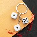 Détail d'un porte-clés dés en résine blanche avec anneau argenté, longueur de 7,8 cm - Blanc