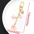 Detalle de dijes de esmalte rosa de rosa y flor de cerezo en un llavero dorado con medidas - Esmalte Rosa Strass Ángel Cordero Rosa (ER1501)
