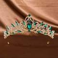 Detailed close-up of a vintage golden crown with emerald green gems and white crystals - Gold Green