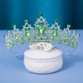 Elegant silver bridal crown with green crystals on white ceramic box and blue background - Silver / Green