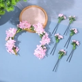 Dettaglio dei fermagli per capelli con fiori rosa e corona con perle su fondo blu - Fascia a Ghirlanda di Fiori Rosa E Forcine / Rosa