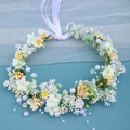Detail view of ivory floral crown with green leaves, pearls, and long white ribbons - Cyan