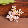 Nahaufnahme der rosa Blumen-Haarspange mit goldenen Metallblättern und Perlen - Gold
