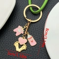 Porte-clés grenouillère rose avec biberon et empreinte dorée sur fond noir chic - Émail Rose Vêtements Coeur Biberon Empreinte (ER1519)
